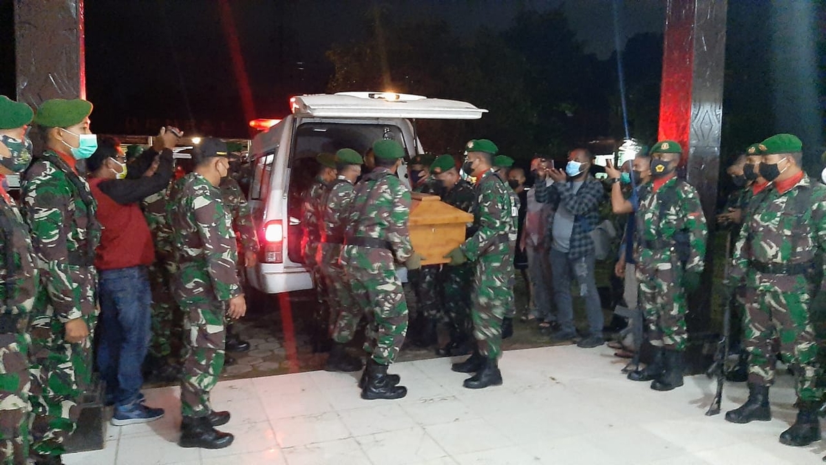 Soldiers carry a coffin into an ambulance at night