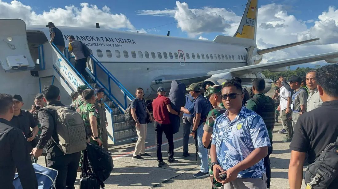 Personel berseragam dan rombongan menaiki pesawat angkut TNI AU di landasan