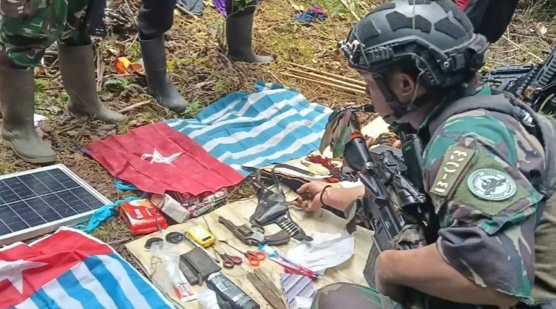 Seorang prajurit memeriksa barang bukti termasuk bendera Bintang Kejora dan senjata api