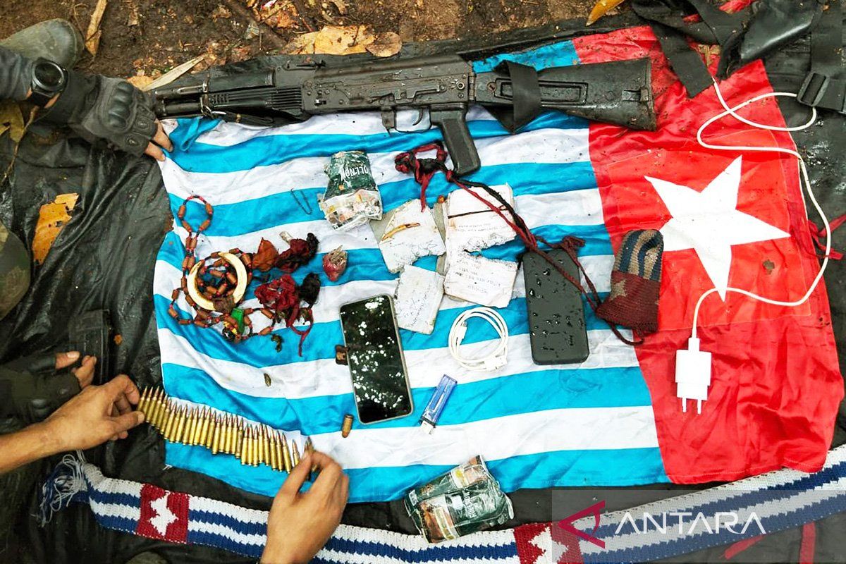 A long-barreled firearm, ammunition and mobile phones lie on a Morning Star flag