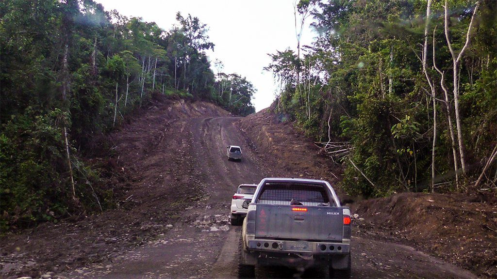 Kendaraan melintasi jalan tanah yang membelah hutan di ruas Trans-Papua Sorong-Manokwari