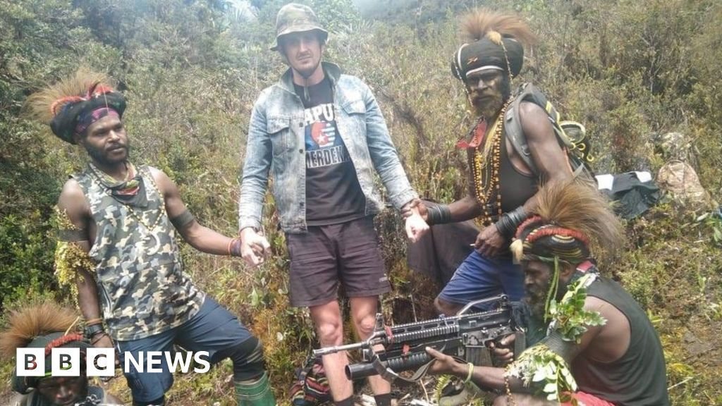 Phillip Mehrtens berdiri dikelilingi tiga pria bersenjata di pegunungan Papua, Februari 2023